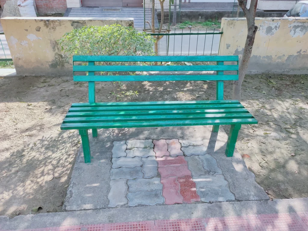 Ağaç gölgelerinin düştüğü taş döşeme üzerinde boş, yeşil bank.